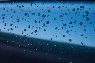 Naklejka na ściany i meble Raindrops on a blue car close-up.