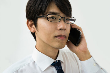 Young Japanese businessman talking on the phone. Isolated on white.