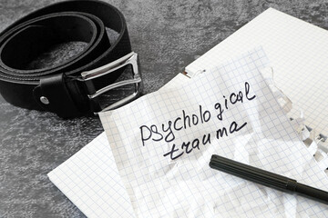 notebook with psychological trauma inscription and dark leather male belt as ptsd symbol on black...