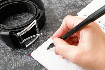notebook with psychological trauma inscription and dark leather male belt as ptsd symbol on black...