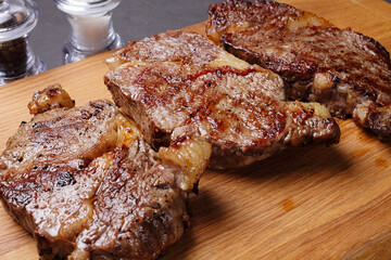 three fried marbled beef steaks on a cutting board, close-up