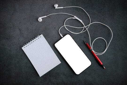 smartphone notepad headphones pen on a gray background, top view, copy space, mock up