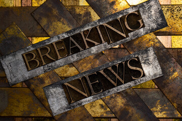 Breaking News text formed with real authentic typeset letters on vintage textured silver grunge copper and gold background