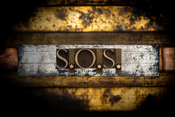 S.O.S. text formed with real authentic typeset letters on vintage textured silver grunge copper and gold background
