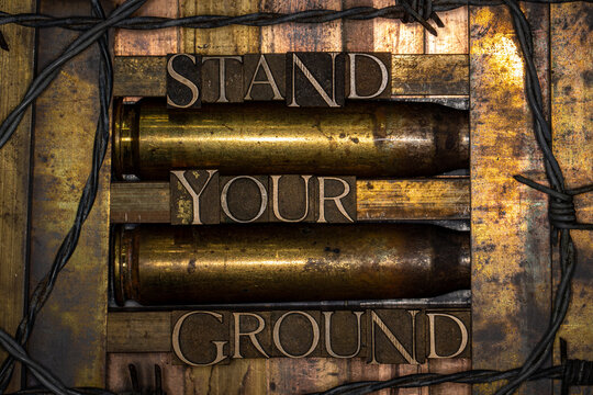 Stand Your Ground text formed with real authentic typeset letters on vintage textured silver grunge copper and gold background