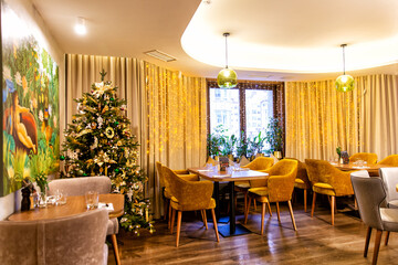 Interior of cozy modern restaurant with Christmas tree and garlands