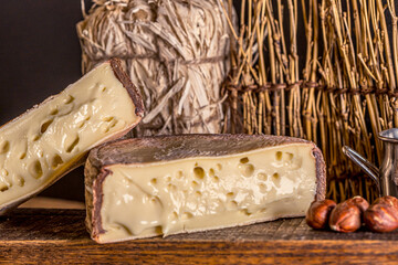 French cheese Saint Nectaire rustic collection delicious. Black background.