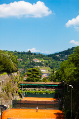 Aerial view. People are playing tennis near the wall of medieval castle in Brescia, Lombardy, Italy. Open air summer activities in the green Italian park.