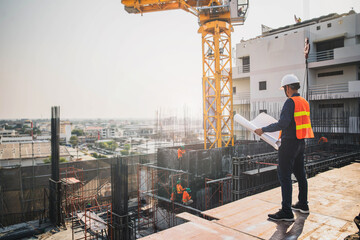 Engineer in hardhat and orange jacket posing on building site. civil engineer or architect with...