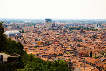 Obraz premium Aerial view of the historical center of Brescia (Lombardy, Italy) with tiled red roofs, chimneys, cathedral's domes and tall white brick old towers. Traditional European medieval architecture. 