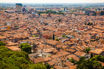 Aerial view of the historical center of Brescia (Lombardy, Italy) with tiled red roofs, chimneys, cathedral's domes and tall white brick old towers. Traditional European medieval architecture. 