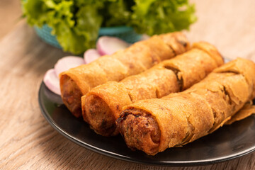 fried spring rolls and vegetables on wood