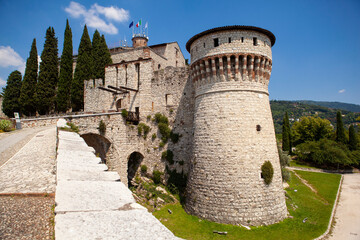 Fototapeta na wymiar A medieval fortress (castle) with watchtowers, a trench and a walk-in bridge in front of the entrance made of white stones (bricks) in the center of the Italian city of Brescia (Lombardy, Italy).