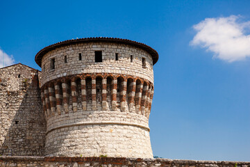 A medieval fortress (castle) with watchtowers, a trench and a walk-in bridge in front of the entrance made of white stones (bricks) in the center of the Italian city of Brescia (Lombardy, Italy).