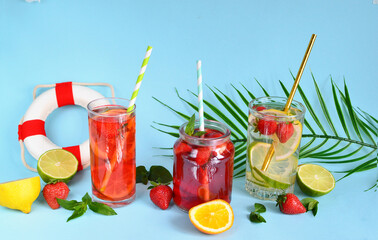 Refreshing summer drinks of lemon, lime, strawberry, orange, mint on a blue background. Detox, healthy eating, fitness drinks. Travel concept.Copy space.