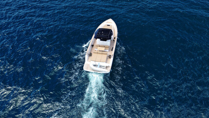 Aerial drone top down photo of small power boat with wooden deck cruising in deep blue...