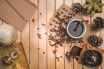 black coffee and coffee beans with compass, map world on the table wooden background. concept Travel