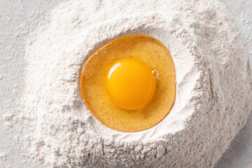 Fresh egg in a heap of wholemeal flour on a marble table. healthy diet concept. close-up. top view. horizontal image.