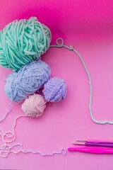 Pink yarn for knitting, knitting needles and hooks. Pink background. Needlework concept.