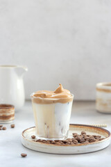 Iced Dalgona Coffee with fluffy sweet foam in a glass on a gray background. trendy summer drink. vertical image. copy space.