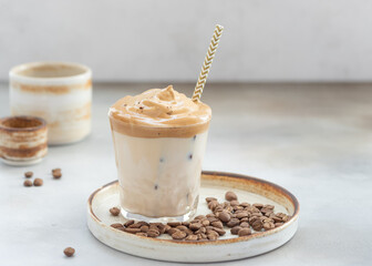 Dalgona Coffee with sweet foam and ice in a glass with a straw. whipped instant coffee. Gray background. horizontal image. place for text.
