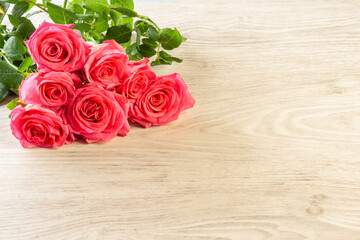 Light wooden background with a composition of pink roses