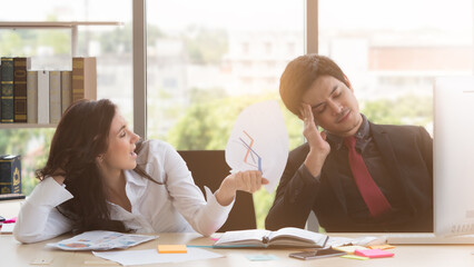 Caucasian businesswoman sitting next to Asian businessman, crumpled up papers with anger. Stressful, unsuccessful business