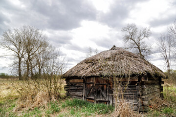 Kudrichi, Belarus 04/27/2020: Old houses and sheds with a roof covered with reeds using old-fashioned technology in the Polesie region in the south-west of Belarus.