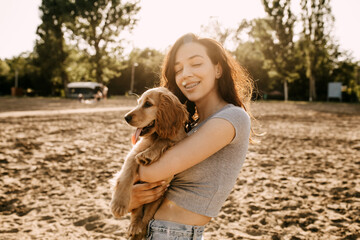 Young brunette woman holding and hugging her little dog, cocker spaniel breed puppy.