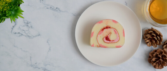 Strawberry roll cake and tea on white stone table. Top view