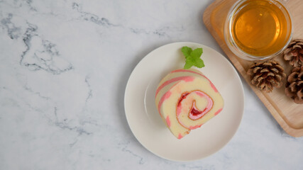 Strawberry roll cake and tea on white stone table. Top view