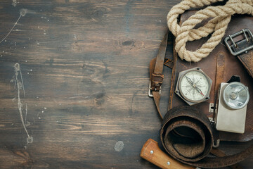 Old travel equipment and adventurer accessories on the wooden table flat lay background.