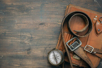 Compass and old leather bag on the adventurer table flat lay background with copy space.
