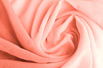 Coral pink delicate fabric draped and spun. Closeup.