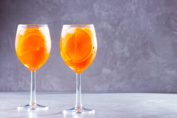 Aperol spritz cocktail on gray background. Two glasses of aperol spritz with orange slised. Summer cocktail in glass. Copy space