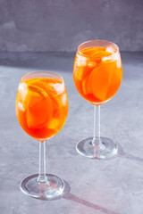 Aperol spritz cocktail on gray background. Two glasses of aperol spritz with orange slised. Summer cocktail in glass. Copy space