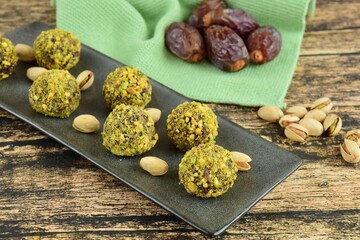 Date Pistachio Chocolate Energy Balls on Wooden Background. Vegan Snack