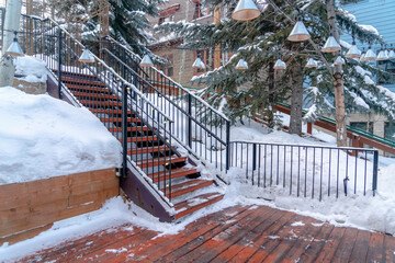 Stairs and wooden deck on snowy hill with decorative and colorful string lights