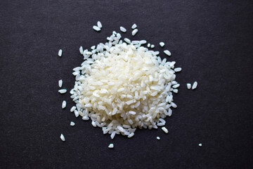 White rice for pilaf spread on a black surface