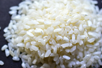 White rice for pilaf spread on a black surface