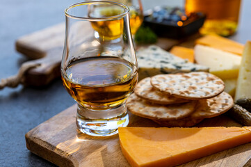Whiskey and cheese pairing, tasting whisky glasses and plate with sliced cheeses