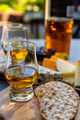 Whiskey and cheese pairing, tasting whisky glasses and plate with sliced cheeses