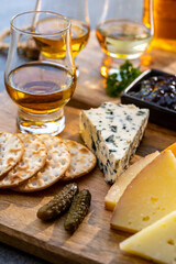 Whiskey and cheese pairing, tasting whisky glasses and plate with sliced cheeses