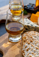 Whiskey and cheese pairing, tasting whisky glasses and plate with sliced cheeses