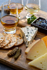 Whiskey and cheese pairing, tasting whisky glasses and plate with sliced cheeses