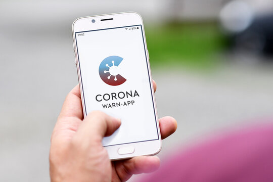 Germany - June 2020: Official German Corona Warning App on mobile phone held by hand on blurry background