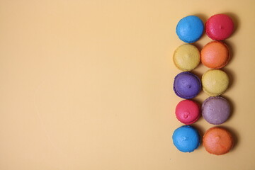 Fototapeta na wymiar Macaroons of differrent colours in a line isolated on yellow background flat lay