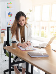 smart asian officer write report on paper, she sitting and feeling happy in work time, strategy analyze and information data research, management organization