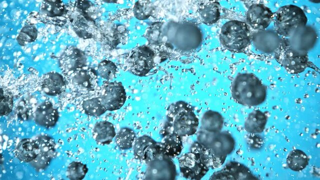 Super Slow Motion Shot of Flying and Splashing Fresh Blueberries on Blue Gradient Background at 1000fps.