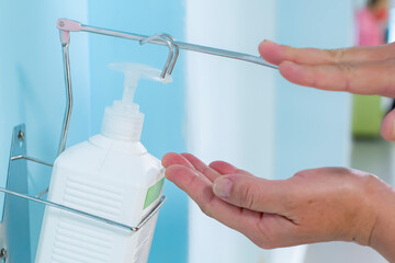 Close-up hand sanitizer disinfection of hands with antiseptic bottle on the wall in hospital